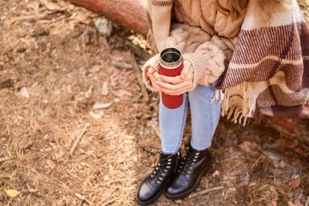 Young woman with flask drinking hot tea in forestの写真素材