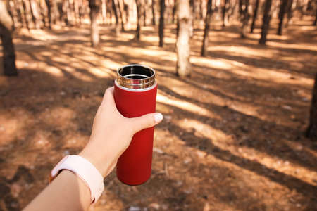 Young woman with flask in forest