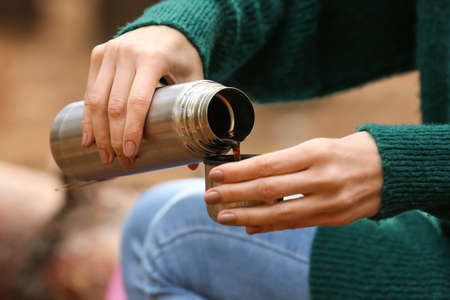 Female tourist with thermos drinking hot tea in forest closeupの写真素材