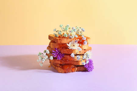 Tasty sandwich with sweet jam and flowers on color backgroundの写真素材