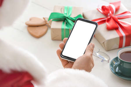Santa Claus with mobile phone at tableの写真素材