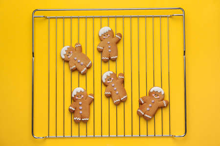 Grill with tasty gingerbread cookies on color background