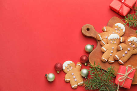 Tasty gingerbread cookies and Christmas decor on color background