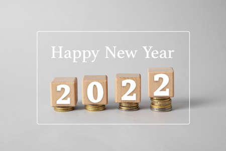 Cubes with figure 2022, coins and text HAPPY NEW YEAR on gray background