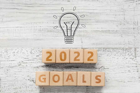 Composition with drawn light bulb and text 2022 GOALS on wooden background