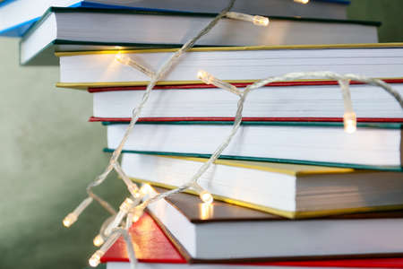 Stack of books with lights on color background, closeup