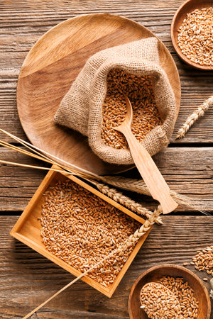 Bag and box with wheat grains on wooden backgroundの写真素材