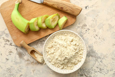Bowl and scoop with banana flour on light backgroundの写真素材