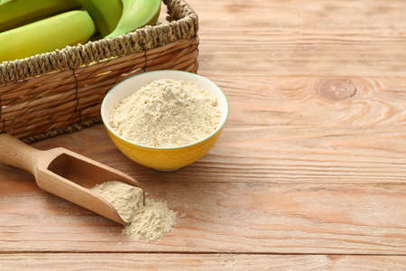 Bowl and scoop with banana flour on wooden backgroundの写真素材