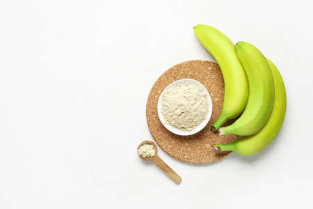 Tasty bananas and bowl with flour on white backgroundの写真素材