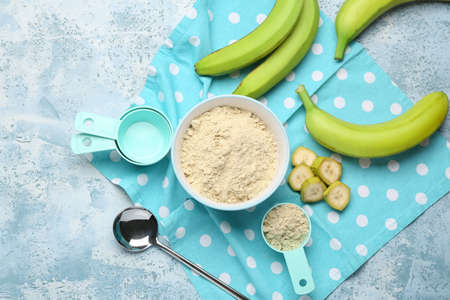 Bowl and spoon with banana flour on color backgroundの写真素材