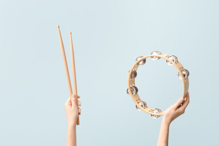 Woman holding drumsticks and tambourine on color backgroundの写真素材