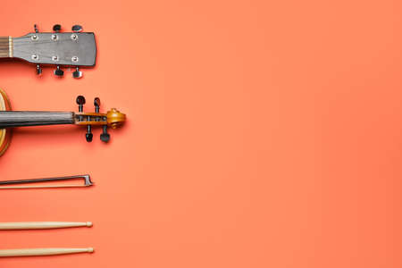 Acoustic guitar, violin, bow and drumsticks on color backgroundの写真素材