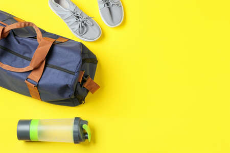 Sports bag, shoes and bottle of water on color backgroundの写真素材