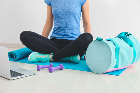 Young woman with sports bag and yoga mat in gym