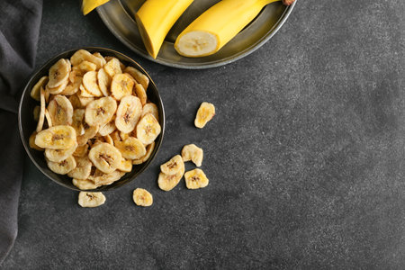 Fresh bananas and crispy chips on dark backgroundの写真素材
