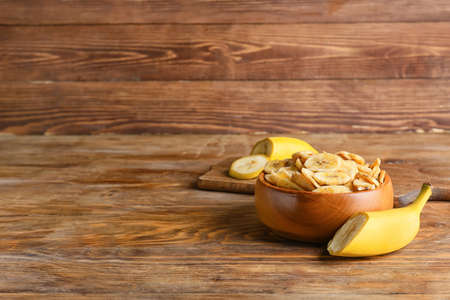 Fresh bananas and crispy chips on wooden tableの写真素材