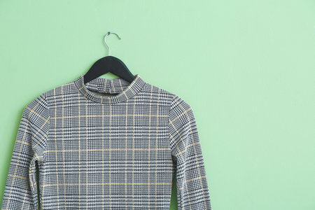 Hanger with stylish clothes on color background