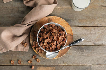 Bowl with tasty cornflakes on wooden background