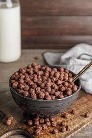 Bowl with tasty chocolate corn balls on wooden background