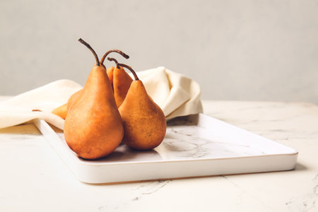 Tray with fresh ripe pears on light background