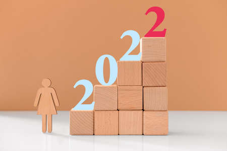 Wooden cubes with figure 2022 on color background