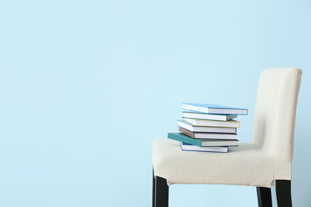 Stack of books on chair near color wallの写真素材