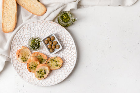 Plate with fresh bread, garlic and olives on light backgroundの写真素材