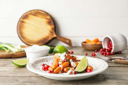 Plate of tasty baked carrot on wooden backgroundの写真素材
