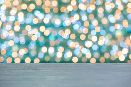 Empty wooden table against blurred Christmas lightsの写真素材