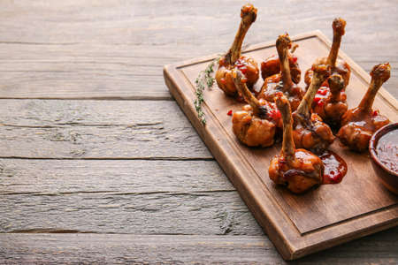 Board with tasty chicken lollipops on wooden backgroundの写真素材