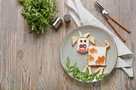 Plate with tasty sandwich in shape of bull on tableの写真素材