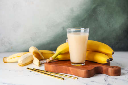 Glass with tasty banana juice on color backgroundの写真素材