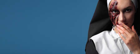 Woman dressed for Halloween as nun on color background with space for textの写真素材