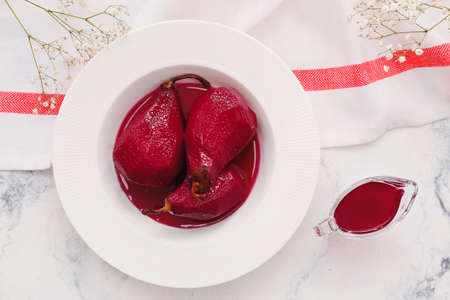 Plate with sweet poached pears in red wine on light background
