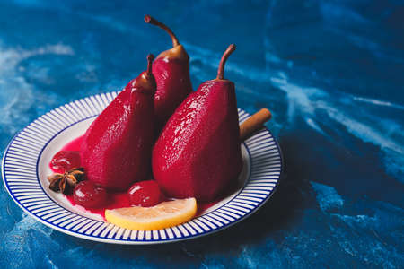 Plate with sweet poached pears in red wine on color backgroundの写真素材