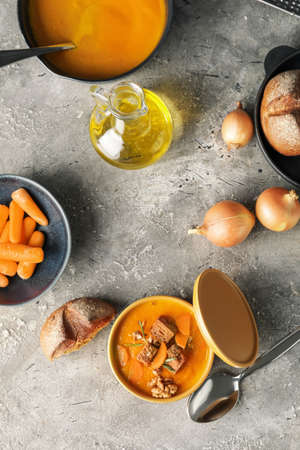 Cooking pot of tasty carrot cream soup on gray backgroundの写真素材