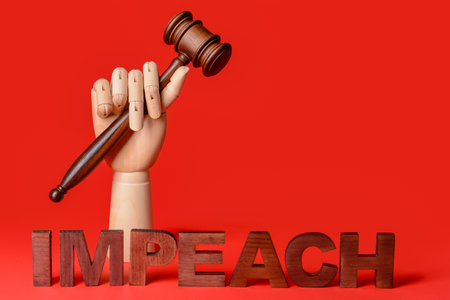 Wooden hand with judge gavel and word IMPEACH on color backgroundの写真素材