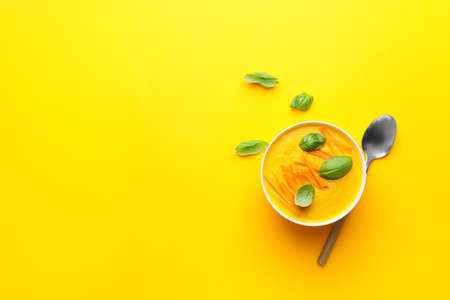 Bowl of tasty carrot cream soup on color backgroundの写真素材