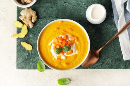 Composition with bowl of tasty carrot cream soup on tableの写真素材