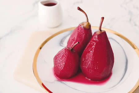 Plate with sweet poached pears in red wine on light backgroundの写真素材