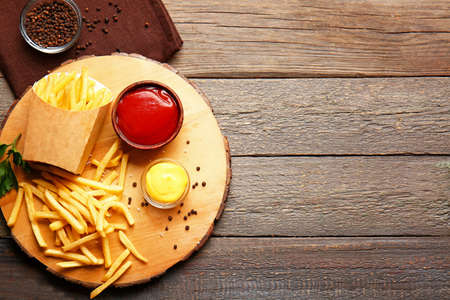 Board with tasty french fries and sauces on table