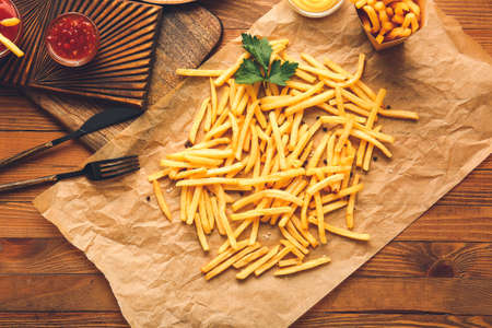 Tasty french fries on wooden background