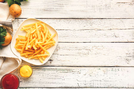 Plate with tasty french fries and sauces on tableの写真素材