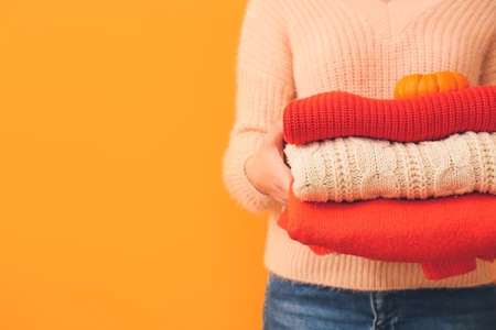 Woman with autumn clothes on color background, closeup