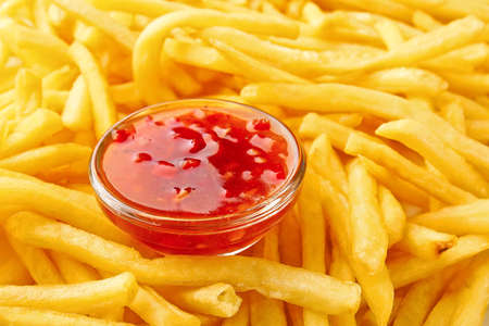Bowl of tomato sauce on heap of french fries