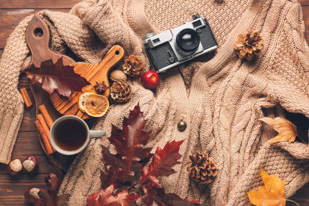 Autumn composition with stylish clothes, photo camera and cup of tea on wooden backgroundの写真素材