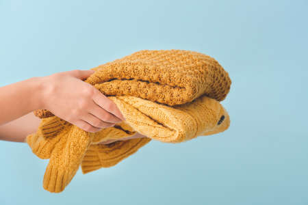 Female hands with warm clothes on color backgroundの写真素材