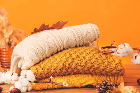 Autumn composition with stylish clothes on table against color background