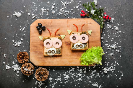 Board with tasty sandwiches in shape of bull and New Year decor on dark backgroundの写真素材